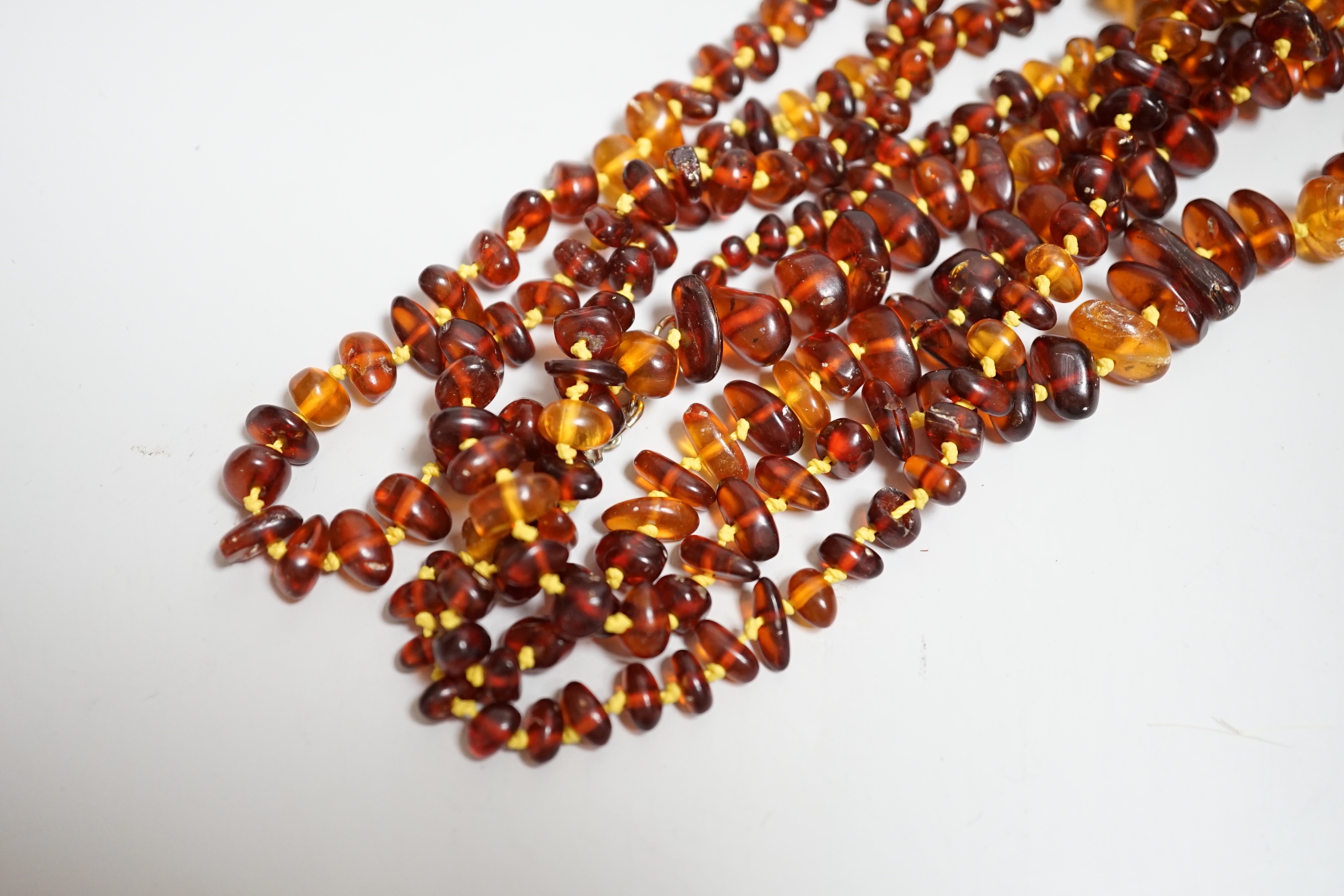 Five assorted single strand amber bead necklaces.